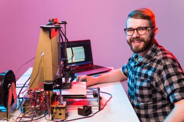 Laboratuvarda 3D yazıcı kullanan ve ürün prototipi, teknoloji ve yenilik kavramını inceleyen genç bir erkek tasarımcı.