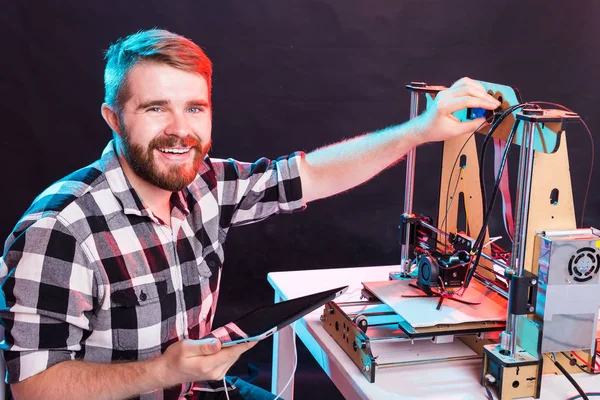 Concepto de tecnología e ingeniería: ingeniero masculino que trabaja de noche en el laboratorio, está ajustando los componentes de una impresora 3D . — Foto de Stock