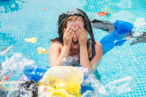 Ecology, plastic trash, environmental emergency and water pollution - Screaming woman with a plastic bag over his head in a dirty swimming pool