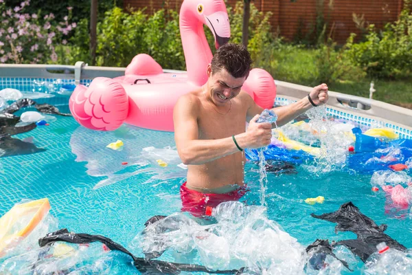 Ecology, plastic trash, environmental emergency and water pollution - shocked man standing in a dirty swimming pool