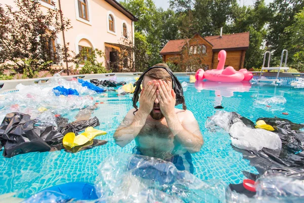 生態系、プラスチックごみ、環境緊急事態と水質汚染-ショックを受けた男は汚れたスイミングプールで泳ぐ — ストック写真