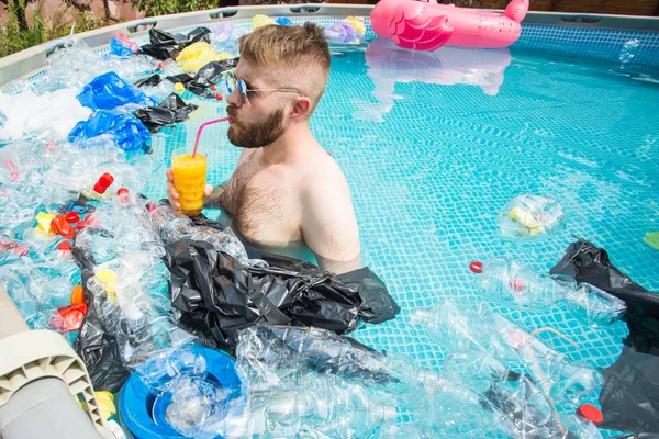 Probleem van afval, plastic recycling, vervuiling en milieu concept - dwaze man zwemmen en plezier hebben in een vervuild zwembad. Flessen en plastic zakken drijven in hun buurt — Stockfoto