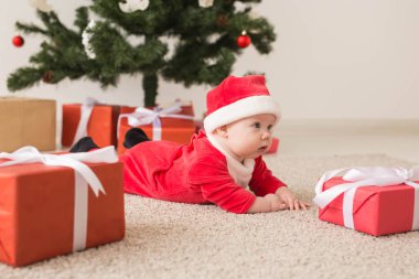 Noel Baba kostümü giyen tatlı bir bebek Noel ağacının üzerinde sürünüyor. Tatil sezonu.