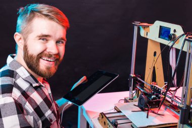 Laboratuvarda 3D yazıcı kullanan ve ürün prototipi, teknoloji ve yenilik kavramını inceleyen genç bir erkek tasarımcı.