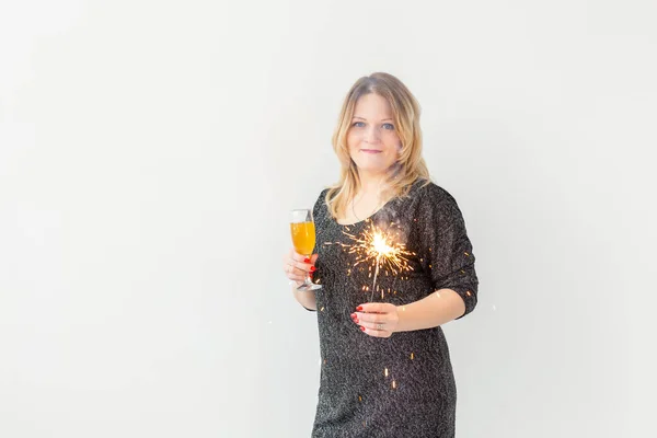 Holidays, christmas, birthday and new year concept - Woman celebrate and holds wine in a glass and sparkler over white background with copyspace — Stock Photo, Image