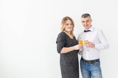 Tatiller, noeller, sevgililer günü ve yeni yıl konsepti - kadın ve erkek şarabı kutluyor ve beyaz arka planda bir bardakta tutuyor.