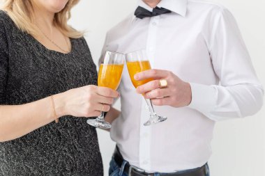 Tatiller, noeller, sevgililer günü ve yeni yıl konsepti - kadın ve erkek şarabı beyaz arka planda yakın planda bir bardakta kutluyor ve tutuyor.