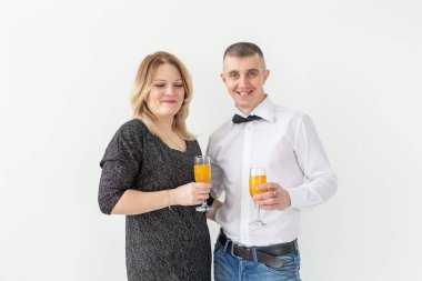 Tatiller, noeller, sevgililer günü ve yeni yıl konsepti - kadın ve erkek beyaz arka planda bir bardakta şarap içip kutluyor