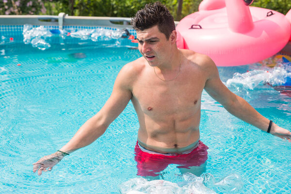 Ecology, plastic trash, environmental emergency and water pollution - shocked man standing in a dirty swimming pool