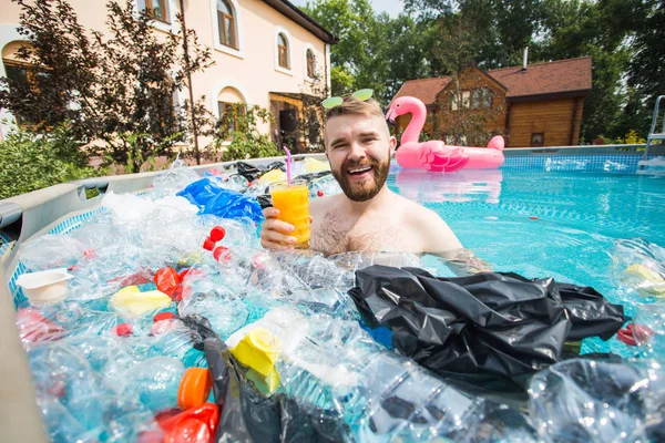 ゴミの問題、プラスチックのリサイクル、汚染と環境の概念-愚かな男は泳ぎ、汚染されたプールで楽しみを持っています。近くにはペットボトルやビニール袋が浮かんでいる。 — ストック写真
