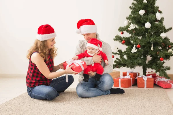 Šťastný pár s dítětem slavit Vánoce společně doma. — Stock fotografie