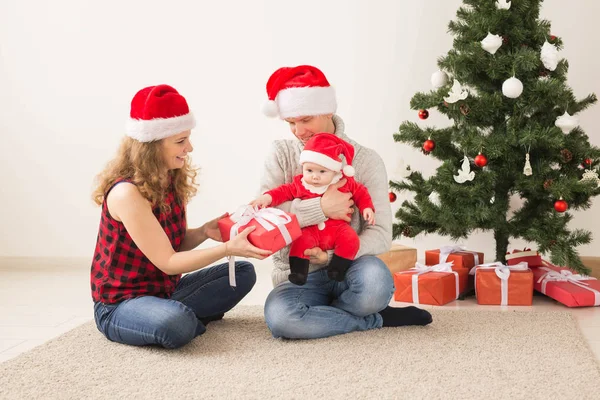 Pareja feliz con el bebé celebrando la Navidad juntos en casa . — Foto de Stock