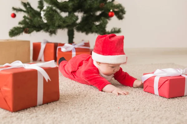 Carina la bambina che indossa la tuta di Babbo Natale strisciando sul pavimento sopra l'albero di Natale. Stagione delle vacanze . — Foto Stock