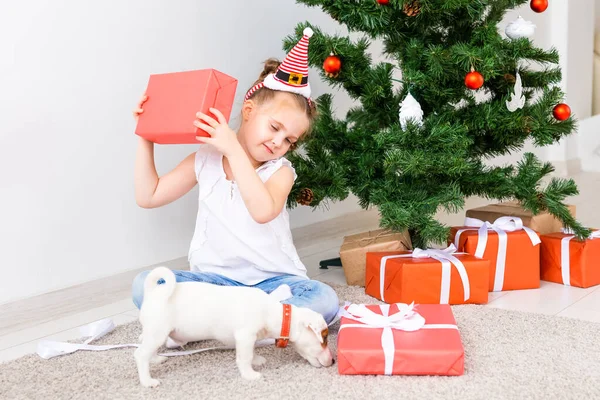Ένα παιδί που ανοίγει χριστουγεννιάτικα δώρα. Παιδί κάτω από το χριστουγεννιάτικο δέντρο με κουτιά δώρων. — Φωτογραφία Αρχείου