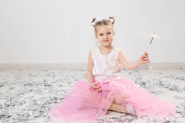 Tatiller, Noel, doğum günü partisi ve yeni yıl konsepti, elinde yanan maytap tutan çocuk. Komik bir partiden sonra.