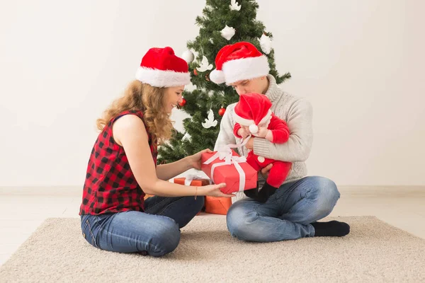Ευτυχισμένο ζευγάρι με μωρό που γιορτάζει τα Χριστούγεννα μαζί στο σπίτι. — Φωτογραφία Αρχείου