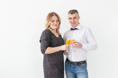 Tatiller, noeller, sevgililer günü ve yeni yıl konsepti - kadın ve erkek şarabı kutluyor ve beyaz arka planda bir bardakta tutuyor.