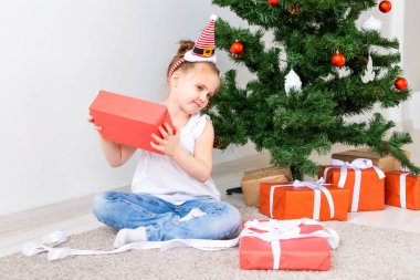 Çocuk Noel hediyelerini açıyor. Noel ağacının altında hediye kutularıyla çocuk.