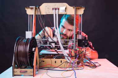 Laboratuvarda 3D yazıcı kullanan ve ürün prototipi, teknoloji ve yenilik kavramını inceleyen genç bir erkek tasarımcı.