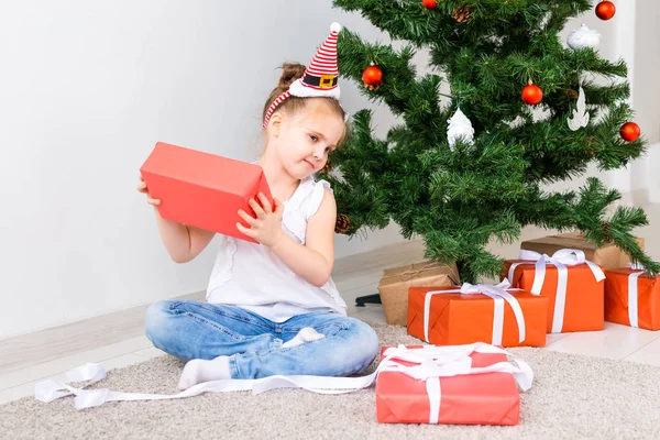 Regali di Natale per l'apertura dei bambini. Bambino sotto l'albero di Natale con scatole regalo . — Foto Stock
