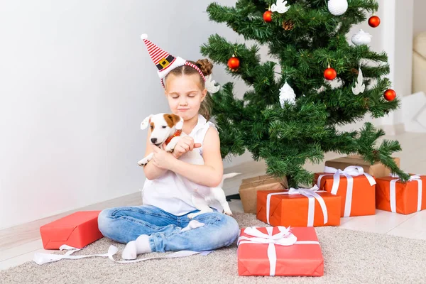 Χριστούγεννα, κατοικίδια ζώα και διακοπές έννοια - Παιδί σε καπέλο Σάντα με ένα Jack Russell τεριέ κουτάβι — Φωτογραφία Αρχείου