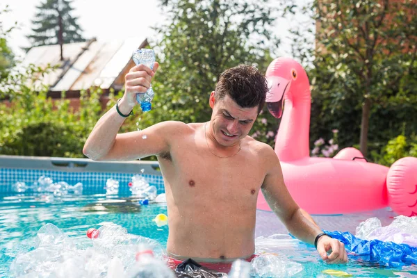 Ecology, plastic trash, environmental emergency and water pollution - shocked man standing in a dirty swimming pool