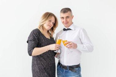 Tatiller, noeller, sevgililer günü ve yeni yıl konsepti - kadın ve erkek beyaz arka planda bir bardakta şarap içip kutluyor