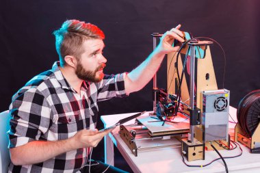 Laboratuvarda 3D yazıcı kullanan ve ürün prototipi, teknoloji ve yenilik kavramını inceleyen genç bir erkek tasarımcı.