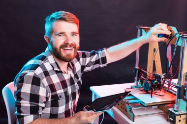 Laboratuvarda 3D yazıcı kullanan ve ürün prototipi, teknoloji ve yenilik kavramını inceleyen genç bir erkek tasarımcı.