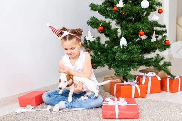 Natale, animali domestici e vacanze concetto - Bambino in cappello di Babbo Natale con un cucciolo jack russell terrier — Foto Stock