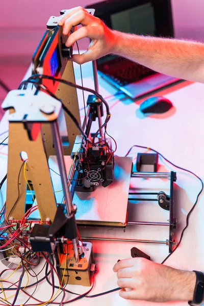 Young male designer engineer using a 3D printer in the laboratory and studying a product prototype, technology and innovation concept