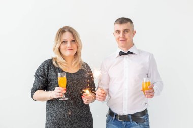 Tatiller, noeller, sevgililer günü ve yeni yıl konsepti - kadın ve erkek beyaz arka planda bir bardakta şarap içip kutluyor