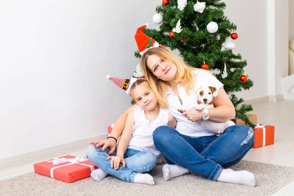 Ευτυχισμένη μητέρα με την κόρη της και τον Τζακ Ράσελ Τεριέ σκύλο που κάθεται κοντά στο χριστουγεννιάτικο δέντρο. — Φωτογραφία Αρχείου