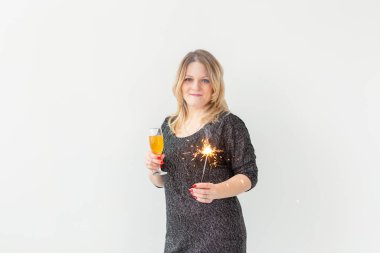 Tatiller, Noel, doğum günü ve yeni yıl konsepti - Kadın şarabı bir bardakta ve beyaz arka planda, kopyalama alanı ile maytap üzerinde kutluyor ve tutuyor