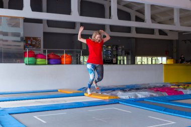 Fitness, eğlence, eğlence ve spor aktivite konsepti - Genç mutlu kadın kapalı bir trambolin üzerinde atlama
