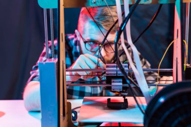 Teknoloji ve mühendislik konsepti - Laboratuvarda gece çalışan erkek mühendis, 3D yazıcı bileşenlerini ayarlıyor.