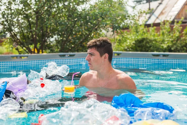 Ecology, plastic trash, environmental emergency and water pollution - shocked man swim in a dirty swimming pool