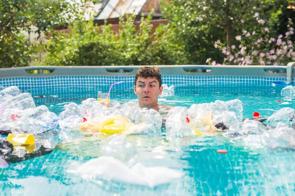 Ecology, plastic trash, environmental emergency and water pollution - shocked man swim in a dirty swimming pool