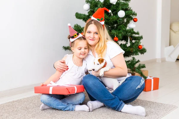 Ευτυχισμένη μητέρα με την κόρη της και τον Τζακ Ράσελ Τεριέ σκύλο που κάθεται κοντά στο χριστουγεννιάτικο δέντρο. — Φωτογραφία Αρχείου