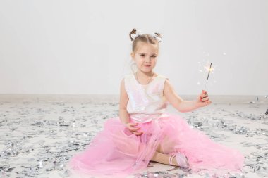 Tatiller, Noel, doğum günü partisi ve yeni yıl konsepti, elinde yanan maytap tutan çocuk. Komik bir partiden sonra.