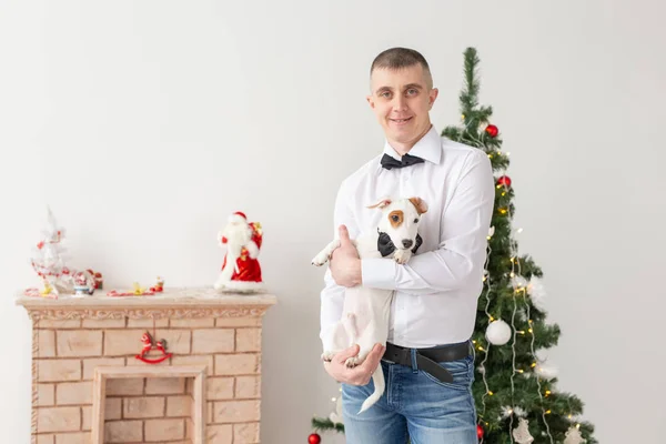 Wakacje i koncepcja zwierzaka - szczęśliwy człowiek i pies w domu z choinką — Zdjęcie stockowe