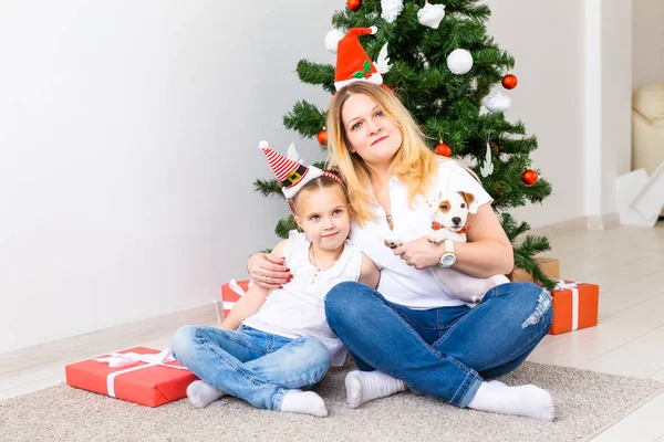 Šťastná matka se svou dcerou a Jack Russell teriér pes sedí v blízkosti vánočního stromečku — Stock fotografie