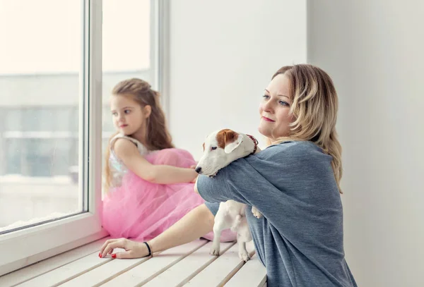 Család és kisállat koncepció - anya és lánya játszik Jack Russell terrier kutya otthon — Stock Fotó