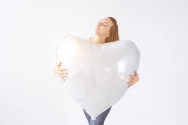 Beyaz arka planda kalp şeklinde hava balonu olan güzel genç bir kadın. Sevgililer gününde bir kadın. Aşkın sembolü