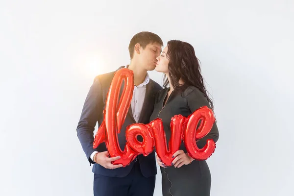 バレンタインデー、休日やギフトの概念。幸せな若いですcaucasianカップル保持愛単語形赤い風船上の白い背景 — ストック写真