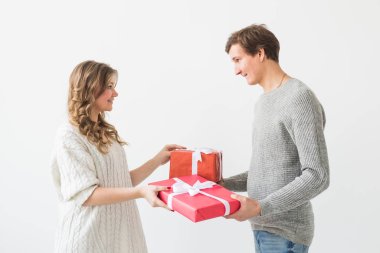 Sevgililer günü, tatil ve hediye konsepti. Sevgililer Günü hediyesi olan mutlu genç çift beyaz bir arka planda izole edilmiş. Mutlu Adam kız arkadaşına hediye veriyor..