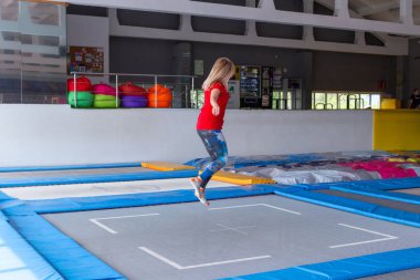 Fitness, eğlence, eğlence ve spor aktivite konsepti - Genç mutlu kadın kapalı bir trambolin üzerinde atlama