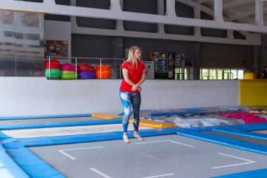 Fitness, eğlence, eğlence ve spor aktivite konsepti - Genç mutlu kadın kapalı bir trambolin üzerinde atlama