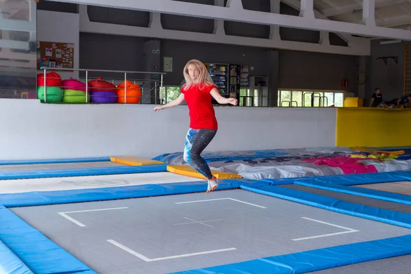 Fitness, diversão, lazer e esporte conceito de atividade - Jovem mulher feliz pulando em um trampolim dentro de casa — Fotografia de Stock