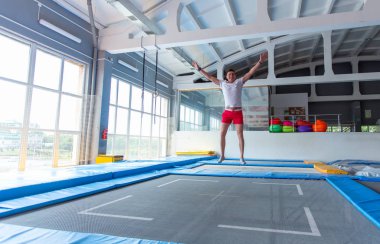 Fitness, eğlence, eğlence ve spor aktivite konsepti - Yakışıklı mutlu adam kapalı bir trambolin üzerinde atlama